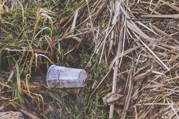 Top view of a plastic glass left on ground. Concept of enviromental issues, ground pollution, ecology problems.