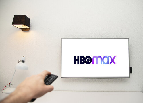 Una televisi&oacute;n con el logo de HBO max en la pantalla. Una habitaci&oacute;n de hotel con una televisi&oacute;n y una mano con un mando a distancia cambiando canales. Viendo pel&iacute;culas en HBO.