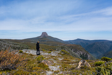 Men stand up in a cliff looking for the horizon with grass and mountains as background in Cradle Mountain, in Tasmania, Australia