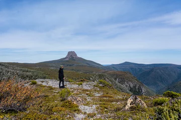 Foto op Plexiglas Cradle Mountain Men stand up in a cliff looking for the horizon with grass and mountains as background in Cradle Mountain, in Tasmania, Australia