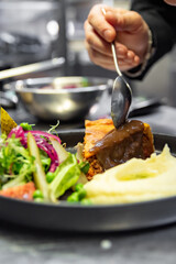 chef hand preparing Meat Pie with mashed potato and salad on restaurant kitchen