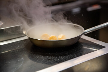 man chef cooking fried shrimp in frying pan on kitchen