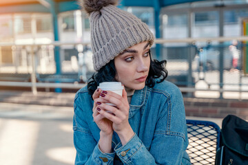 a young woman in a denim jacket is talking on the phone and waiting for a tram, bus at the stop Lifestyle photo