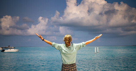 woman looking at pink sunset over tropical sea freedom