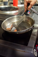 man chef cooking fried salmon fish in frying pan on kitchen