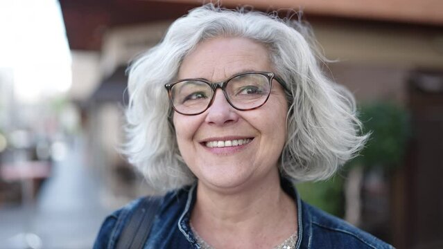 Middle age woman with grey hair smiling confident at street