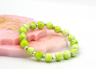 handmade bracelet made of green and silver beads, resting on rose-golden stand. Delicate green...