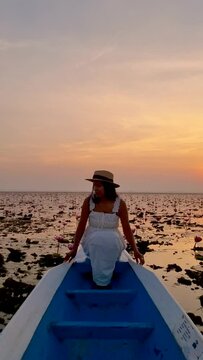 Sunrise at The sea of red lotus, Lake Nong Harn, Udon Thani, Thailand. An Asian woman in a wooden boat during sunrise at the red lotus lake in Thailand 