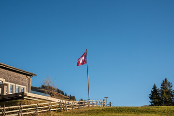 Swiss flag on top of a mountain peak in the Appenzell region in Switzerland