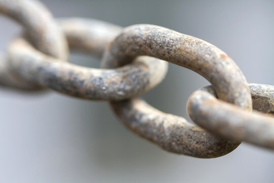 Close up view of rusty metal chain links on a gray background