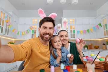 Happy family making selfie while painting Easter eggs in kitchen
