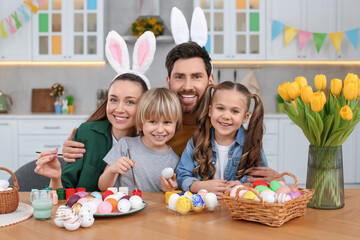Portrait of happy family with Easter eggs at table in kitchen