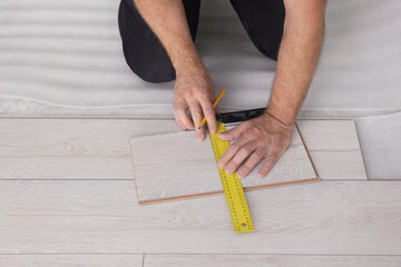 Fototapeta na wymiar Man using measuring tape during installation of laminate flooring, closeup