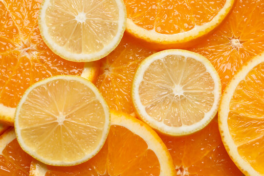 Slices of lemon and orange as background, top view