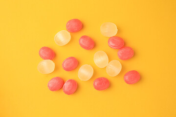 Fototapeta na wymiar Many different colorful cough drops on orange background, flat lay