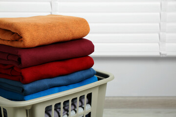 Plastic laundry basket with clean clothes indoors, closeup. Space for text