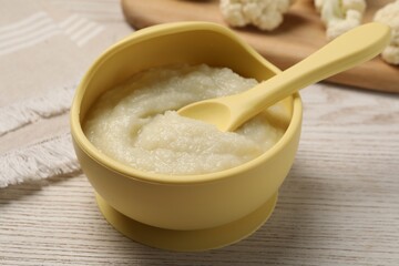 Baby food. Bowl with tasty cauliflower puree on light wooden table