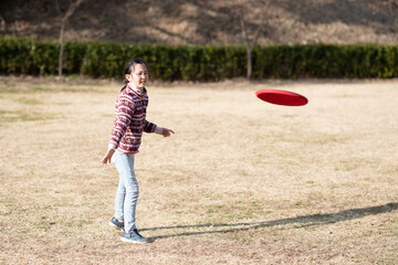Fototapeta premium 冬の公園でフリスビーを飛ばす少女