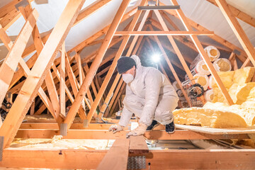 man insulates the roof and ceiling of the house with glass wool
