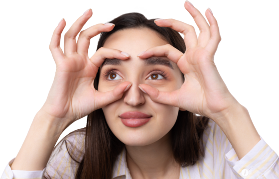 Close up portrait of attractive quirky young woman making binoculars with hands showing ok gesture on white studio background.