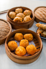 Close up of fried Dimsum in traditional bamboo basket with 
chopsticks on wooden background