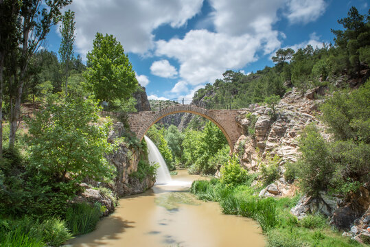 View of Clandras bridge of Usak province with green nature and river and waterfall with blue cloudy sky