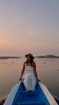 Sunrise at The sea of red lotus, Lake Nong Harn, Udon Thani, Thailand. An Asian woman in a wooden boat during sunrise at the red lotus lake in Thailand 