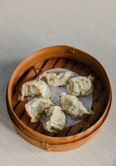 Traditional chinese steamed dumplings Dim Sums in bamboo steamer on white grey background