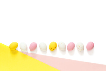 candy Easter eggs on a light white-pink and yellow background. Happy easter. copy space	