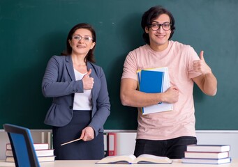 Old female teacher and male student in the classroom