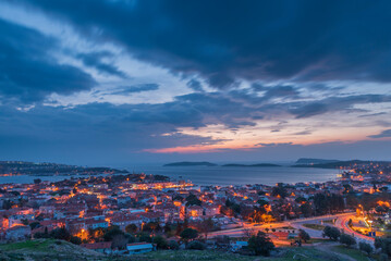 Seaside town with evening lights and blue sky with colorful clouds after sunset