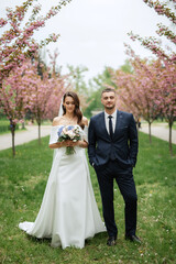 newlyweds walk in the park among cherry blossoms