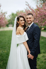 newlyweds walk in the park among cherry blossoms