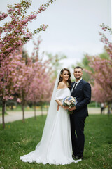 newlyweds walk in the park among cherry blossoms