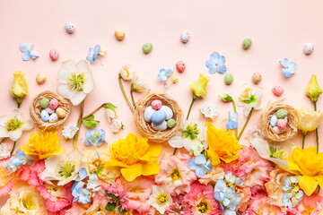 Easter composition with Spring Flowers and Easter eggs in nest on pastel pink background.