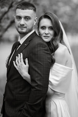 Fototapeta premium newlyweds walk in the park among cherry blossoms