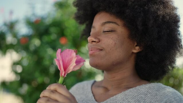 African american woman smiling confident smelling flower at park