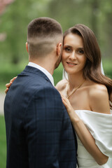 Fototapeta premium newlyweds walk in the park among cherry blossoms