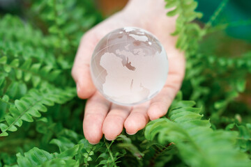 Woman holds a model of planet Earth from glass. Symbol of sustainable development and renewable energy	