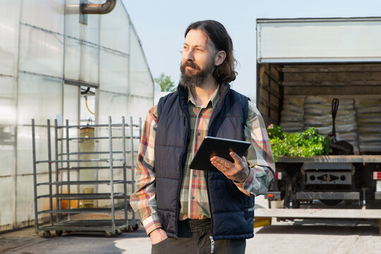 Man farmer holds a tablet in his hands. Growing plants 