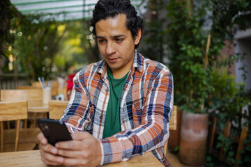 Young Hispanic man outdoors using mobile phone