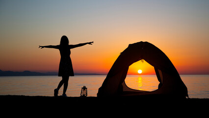 Camping tent woman watching sunset doing yoga with kerosene lamp. a positive energizing sunset...