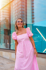 an Asian woman in a pink dress and sunglasses with an umbrella is sitting in the center of the city