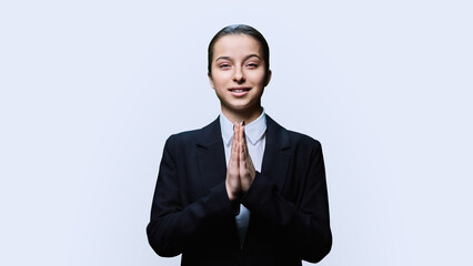 Young female pleading holding her palms together in request, on white background