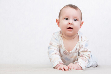 Child on a white background. An adorable six month old baby boy is lying on the bed. Conceptual photo of fatherhood and motherhood.