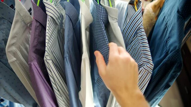 man selects his clothing from clothes rack