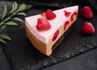 Pieces of cheesecake with raspberries on black board