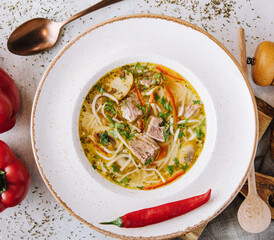 Chicken soup with noodles and vegetables in white bowl