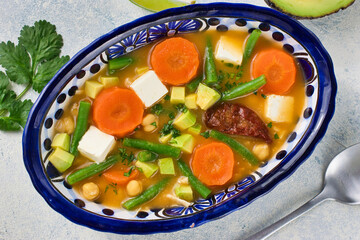 伝統的なメキシコのスープ　カルド・トラルペーニョ　スプーンとパクチーを添えて　俯瞰撮影　Traditional Mexican soup Caldo Tlalpeño served with a spoon and coriander overhead shot