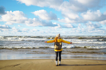 Happy tourist in a yellow jacket standing and looking on sea. Lifestyle, travel, tourism, nature, active life.